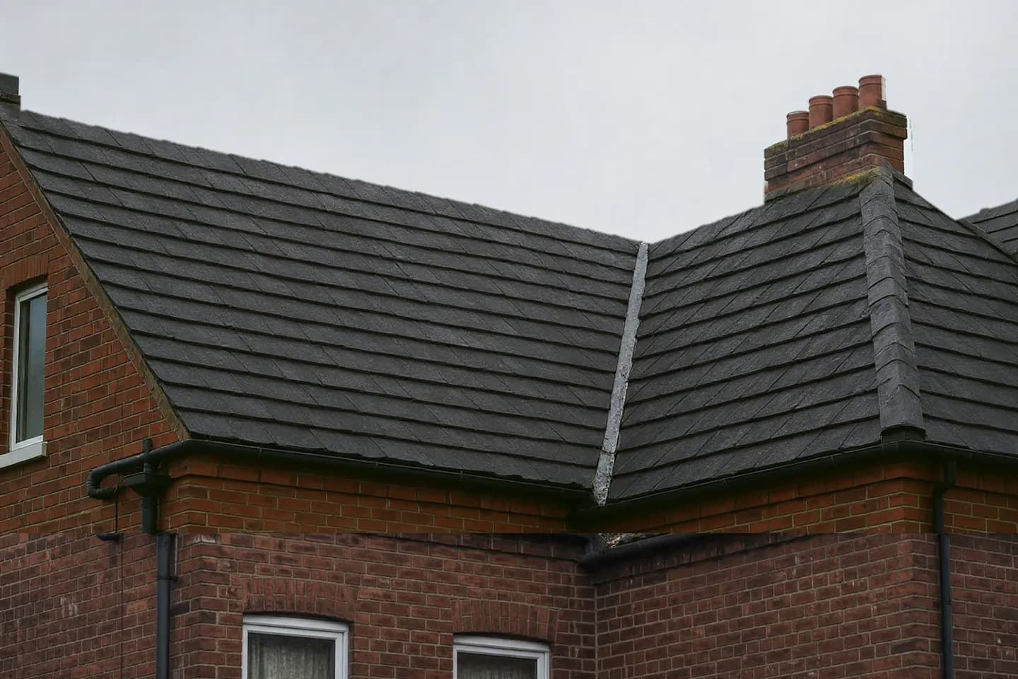 The same roof with clean dark tiles and no moss after professional roof cleaning and moss removal