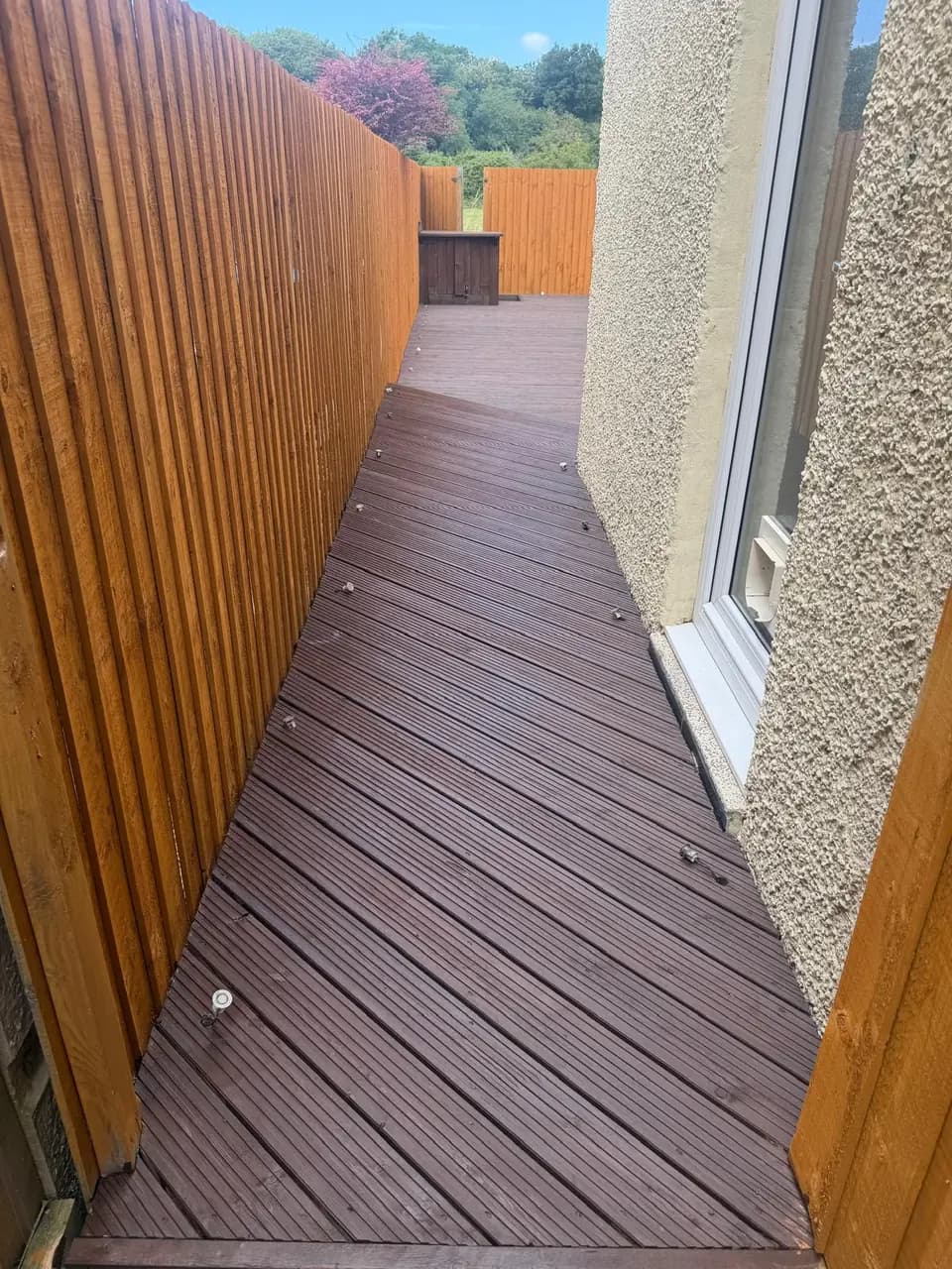 Finished dark decking and warm treated fencing along the narrow side access