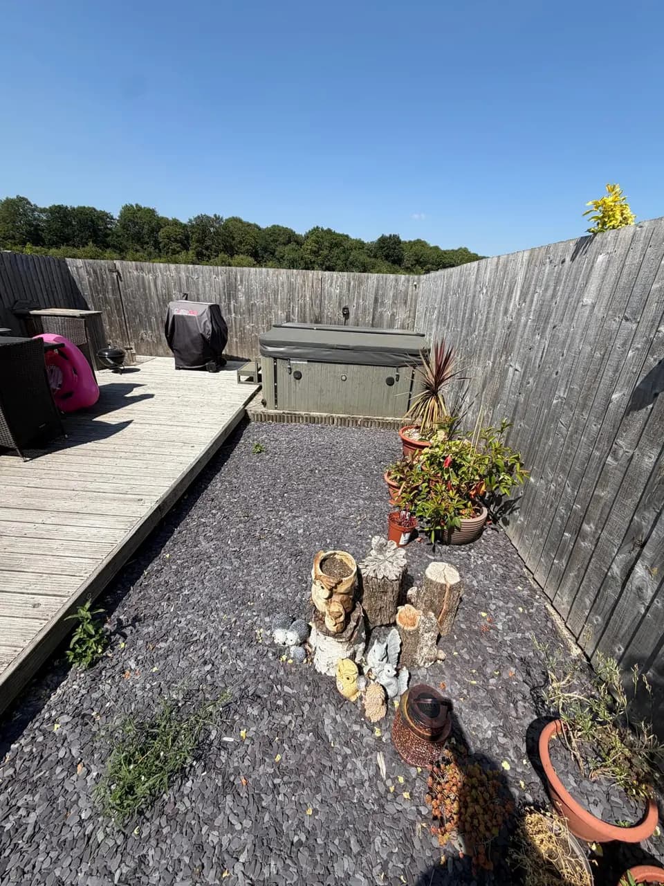 Grey fence boards and untreated decking around a garden seating and hot-tub area