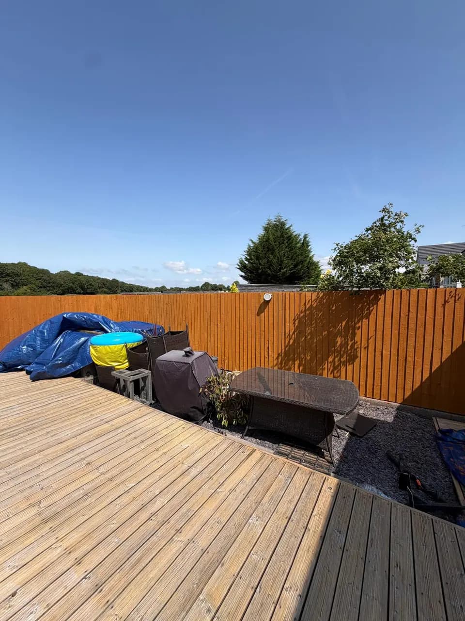 Warm treated fence panels behind a garden seating area during restoration