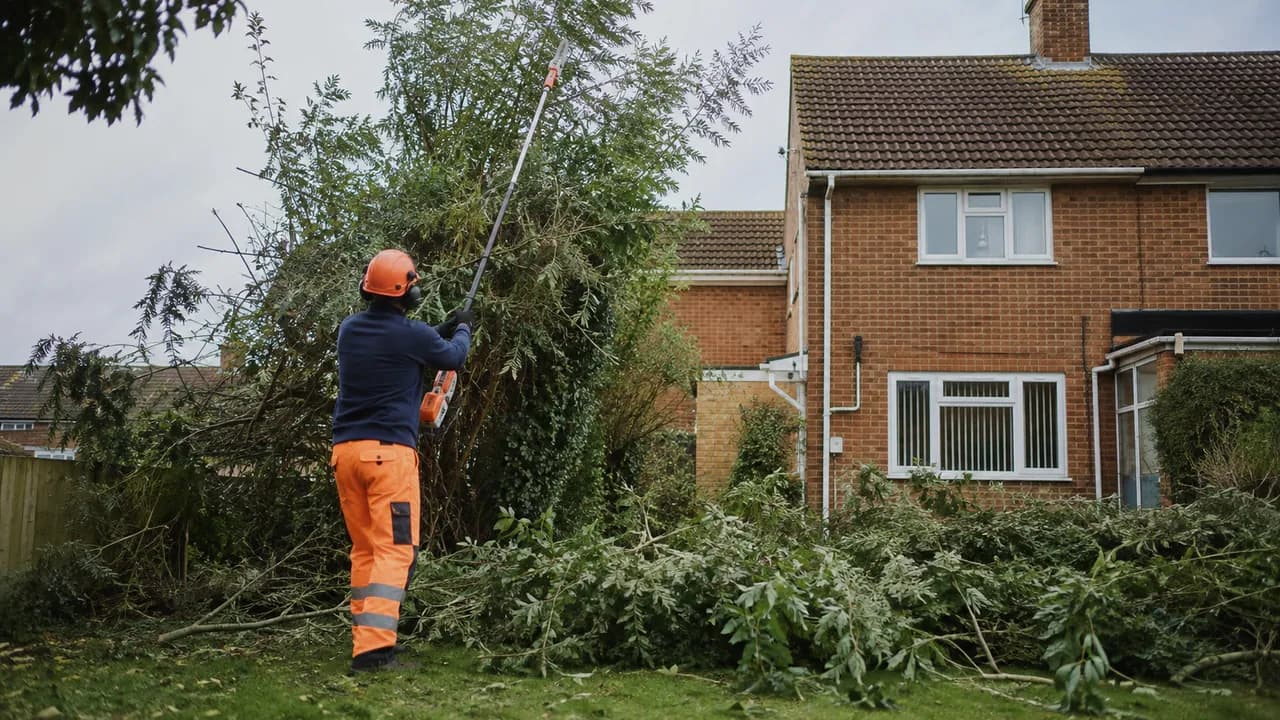 Tree reduction in progress on a 1950s brick semi-detached house on a flat, open Ellesmere Port estate with a tiled roof