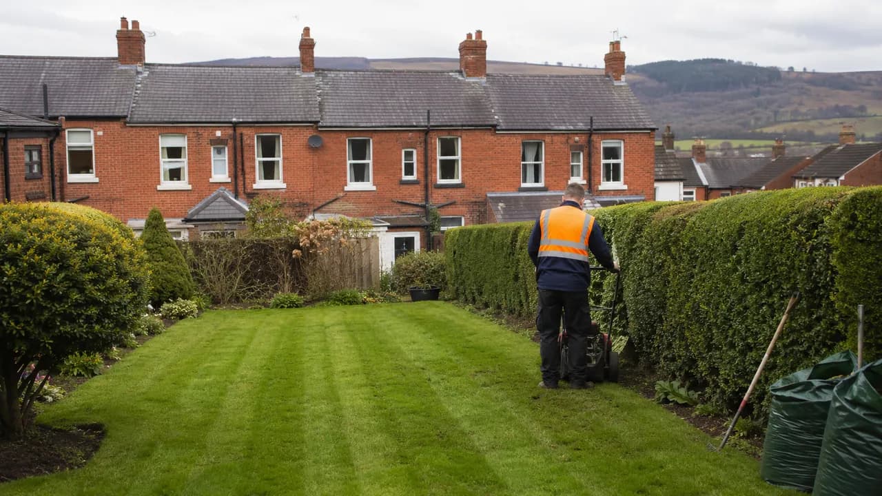 Garden maintenance in progress on a Welsh brick terrace with a slate roof on a Wrexham street, North Wales, hills in the distance