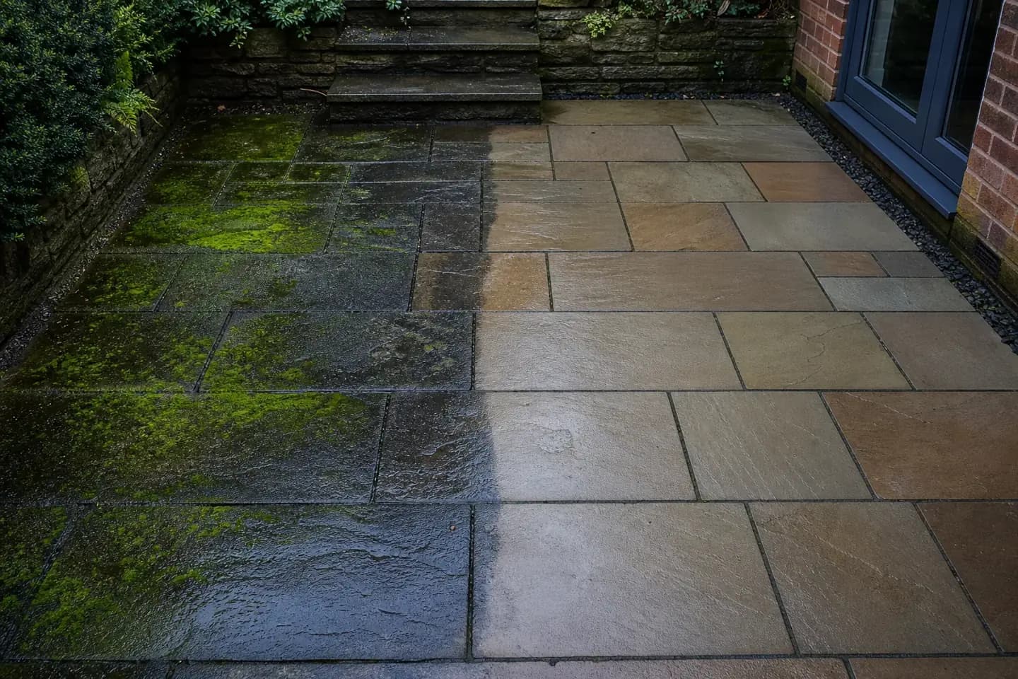 Half-cleaned Indian sandstone patio at a Chester home showing black spotting and green algae lifted to reveal the natural stone colour