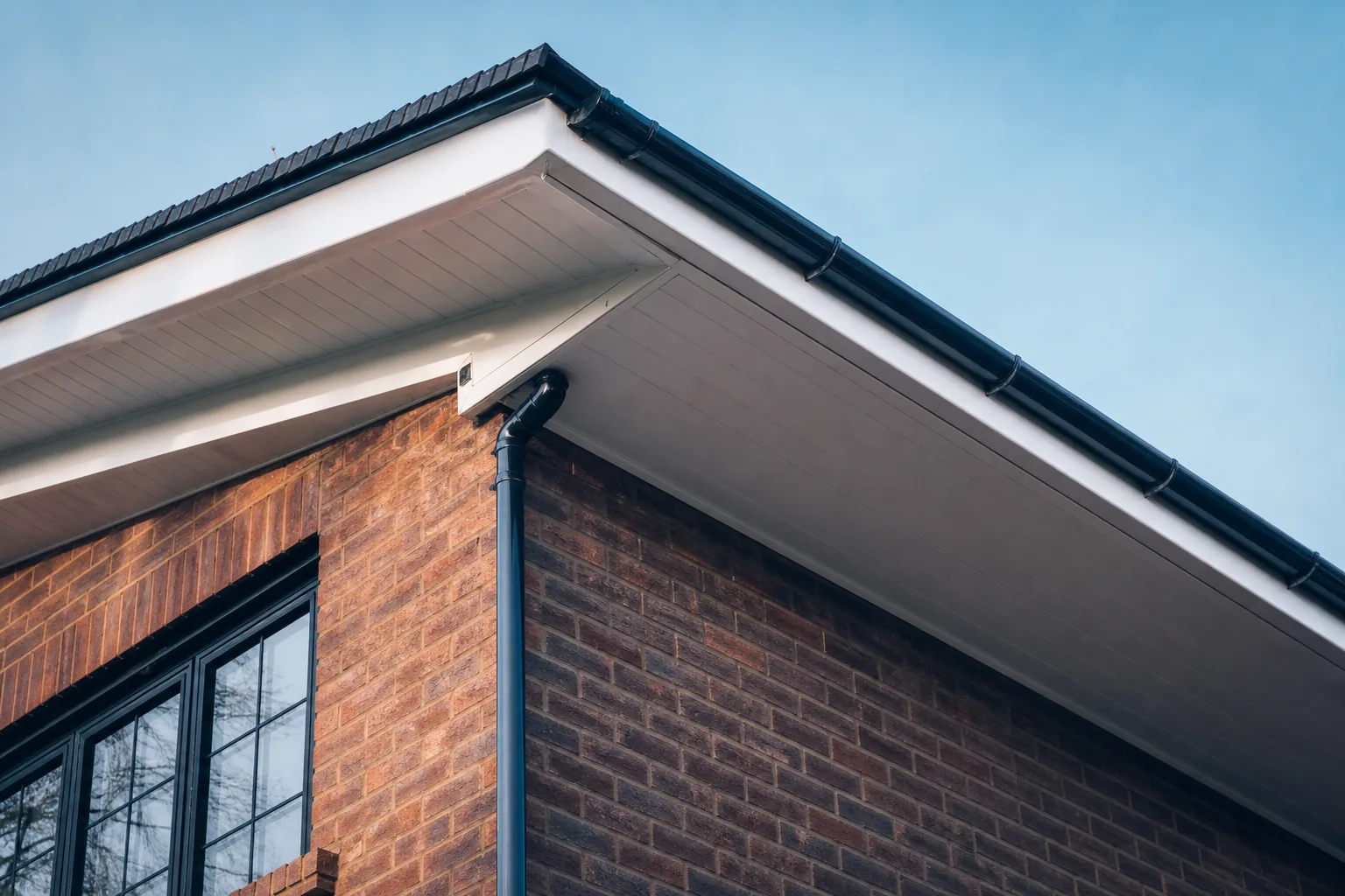 Half-cleaned white uPVC soffit and fascia roofline on a Chester semi showing green algae beside restored bright white boards