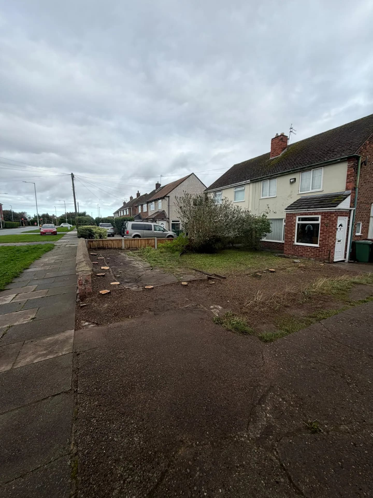 Front garden after Leylandii removal, with a cleared boundary and visible stump tops beside the low wall