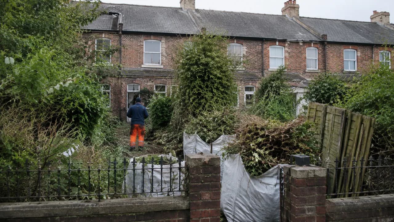 Garden clearance in progress on a Victorian brick terraced house with a slate roof on a Birkenhead street, iron railings and a small front yard