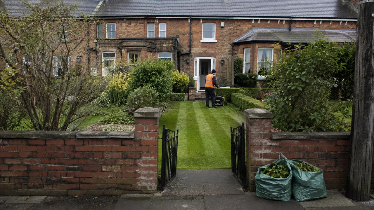Garden maintenance in progress on a Victorian railway-era brick terrace in Crewe with a slate roof, seen from the pavement