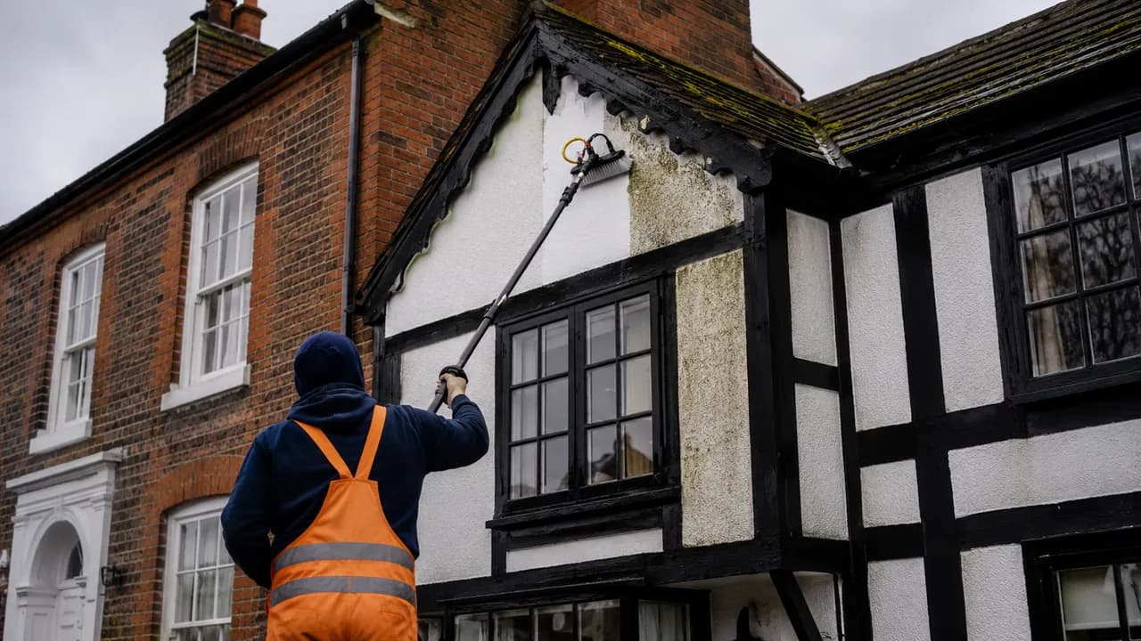Exterior softwash cleaning in progress on a black-and-white timber-framed cottage beside a Georgian brick townhouse in Nantwich, Cheshire